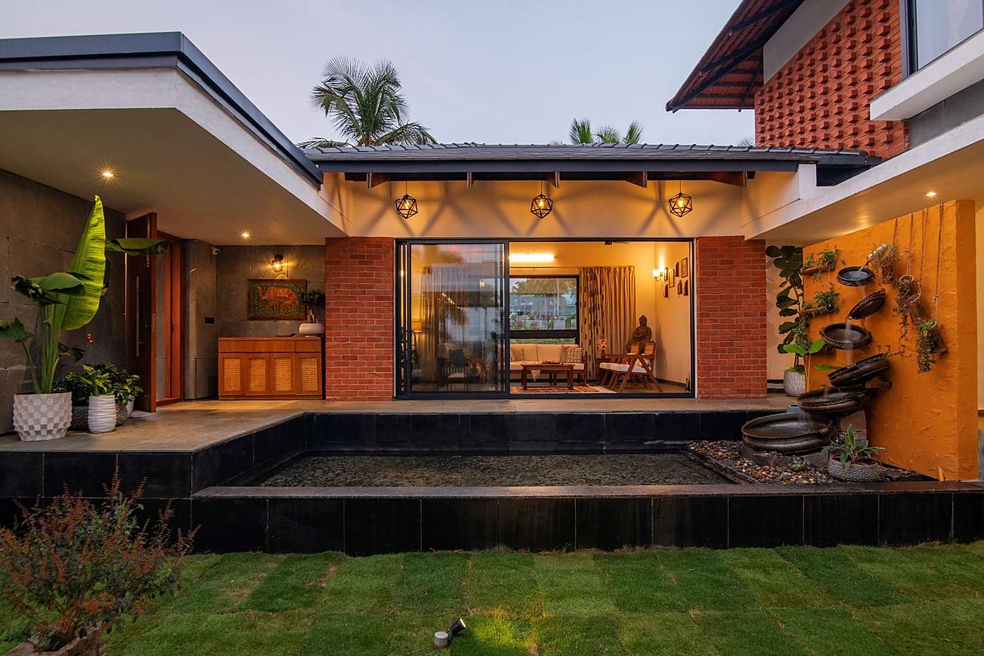 Courtyard elevation with brick columns and water body at dusk